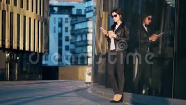 年轻漂亮的女商人带着一杯咖啡，正在城市里用智能手机<strong>办公大楼</strong>